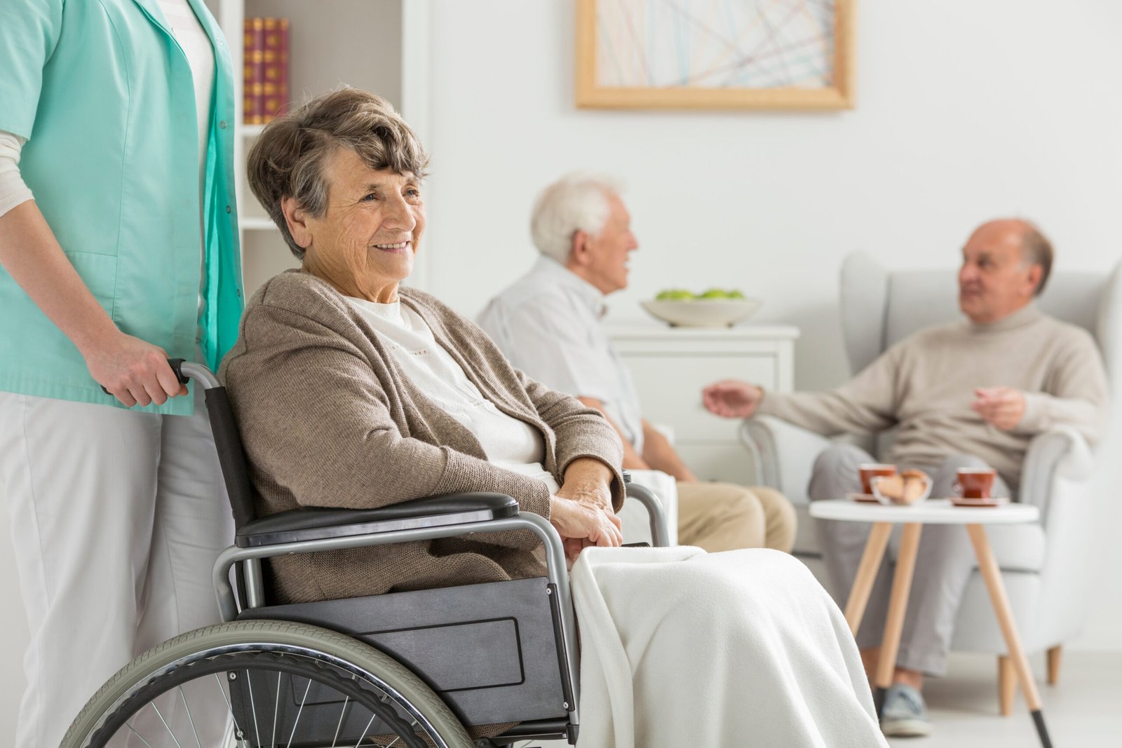 Caregiver gently helping a senior man walk with his walker through a bright living room
